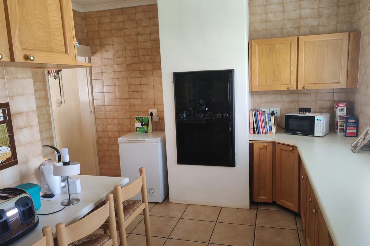 A functional kitchen featuring wooden cabinetry, tiled splashbacks, and tiled flooring, offering a classic layout with a built-in oven.