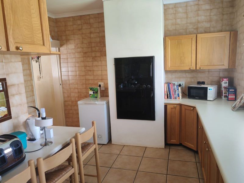 A functional kitchen featuring wooden cabinetry, tiled splashbacks, and tiled flooring, offering a classic layout with a built-in oven.