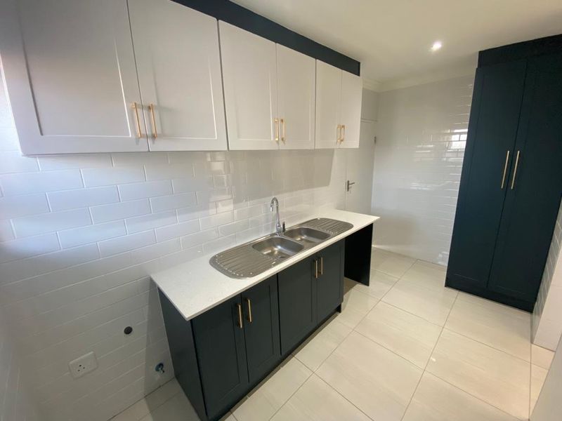 Modern kitchen featuring two-tone cabinetry, stone countertops, double bowl sink, subway tile backsplash, and neutral tiled flooring.