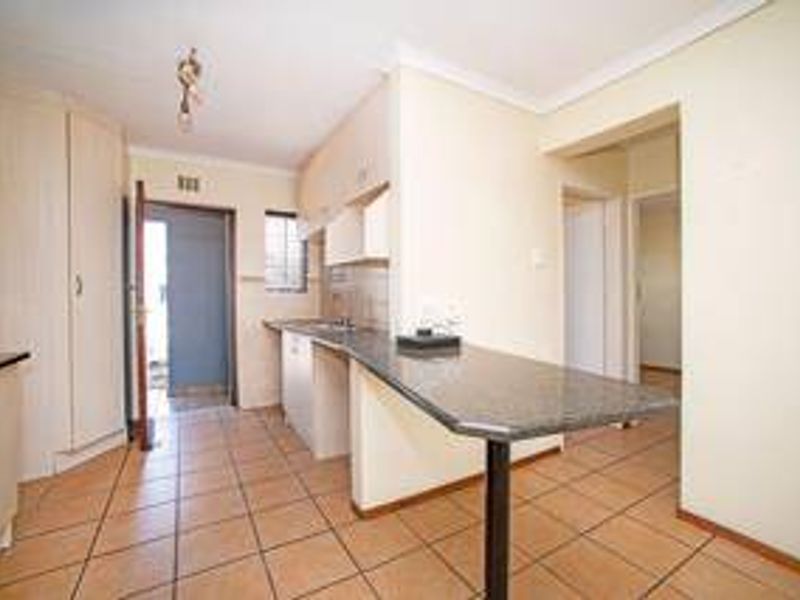 A functional kitchen featuring laminate cabinetry, a granite breakfast bar, and tiled flooring, offering a clean and practical layout for daily use.