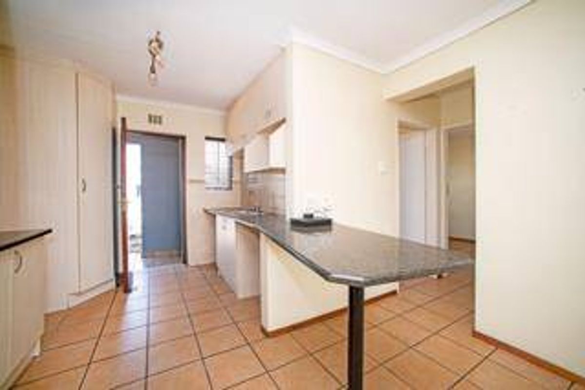 A functional kitchen featuring laminate cabinetry, a granite breakfast bar, and tiled flooring, offering a clean and practical layout for daily use.