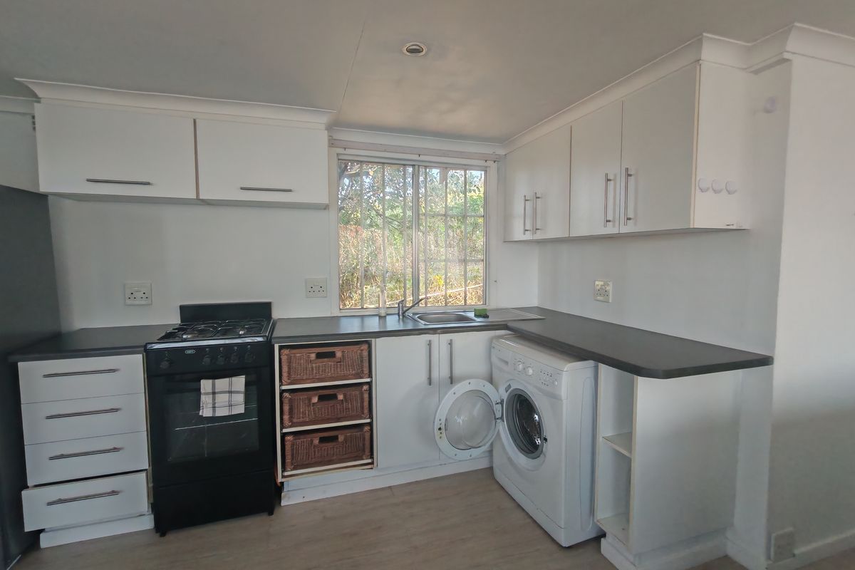 A functional kitchen featuring white cabinetry, dark laminate countertops, a gas stove, and dedicated space for a washing machine.