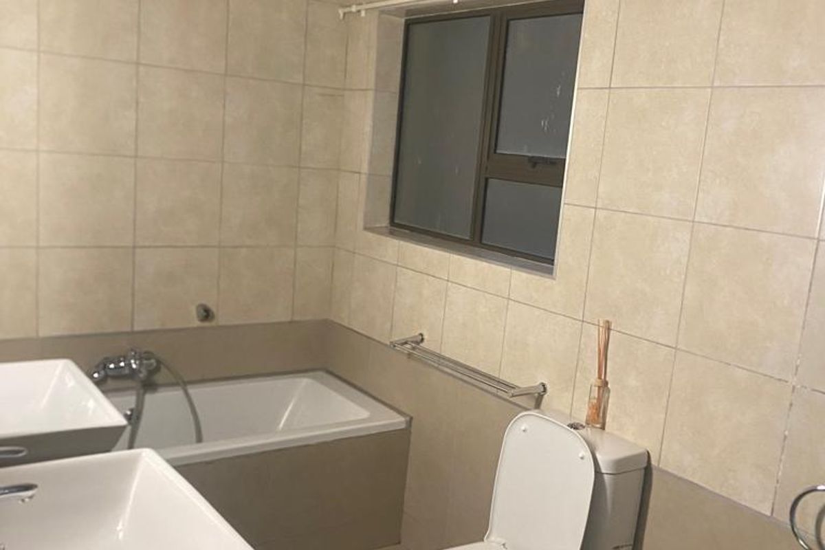 A functional bathroom featuring a built-in bathtub, dual vanity basins with granite countertop, and neutral ceramic tiling throughout.