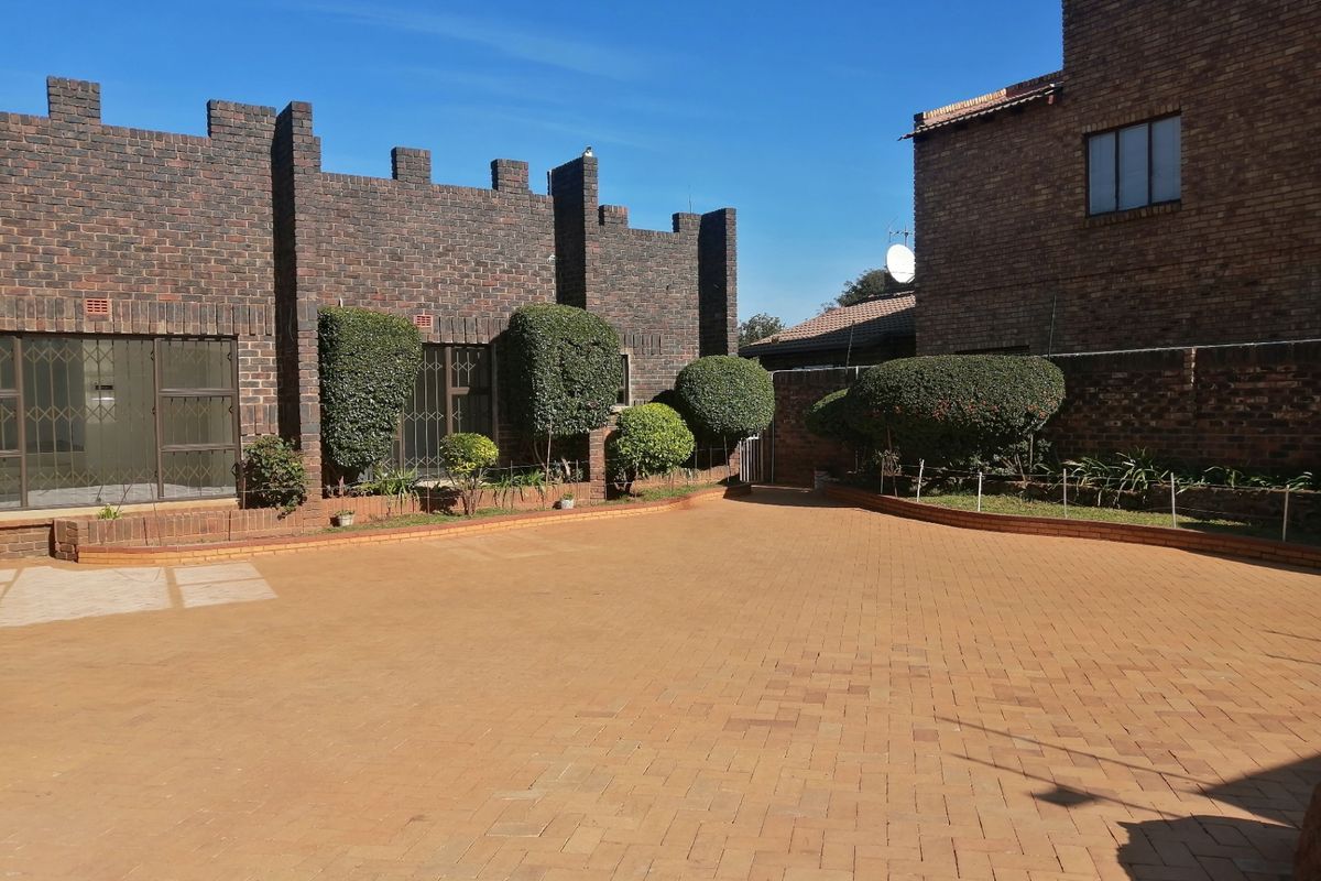 A spacious rear courtyard featuring durable face brick construction, paved flooring, and established garden hedges, providing a private outdoor area.