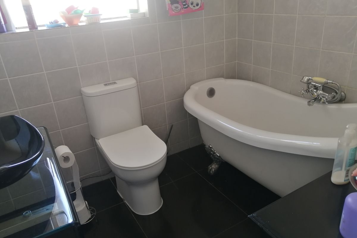 A functional bathroom featuring a classic clawfoot bathtub, a modern toilet, and tiled finishes throughout.