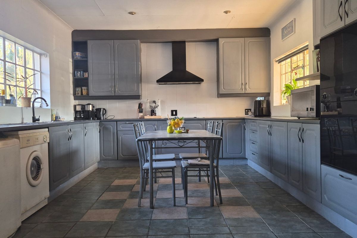 A functional kitchen featuring grey cabinetry, tiled flooring, a built-in oven, and an extractor fan, offering a practical layout with ample storage space.