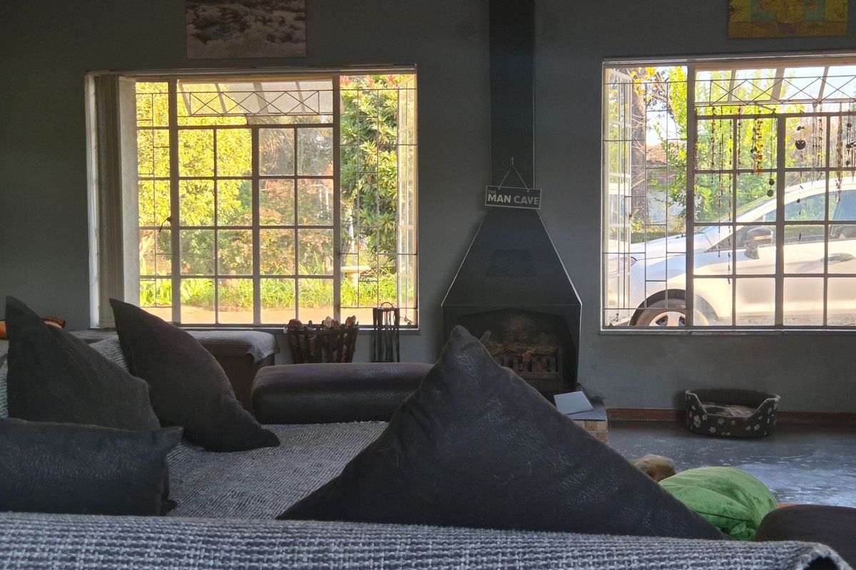 Living room featuring a central freestanding fireplace, large steel-framed windows providing natural light, and durable concrete flooring.