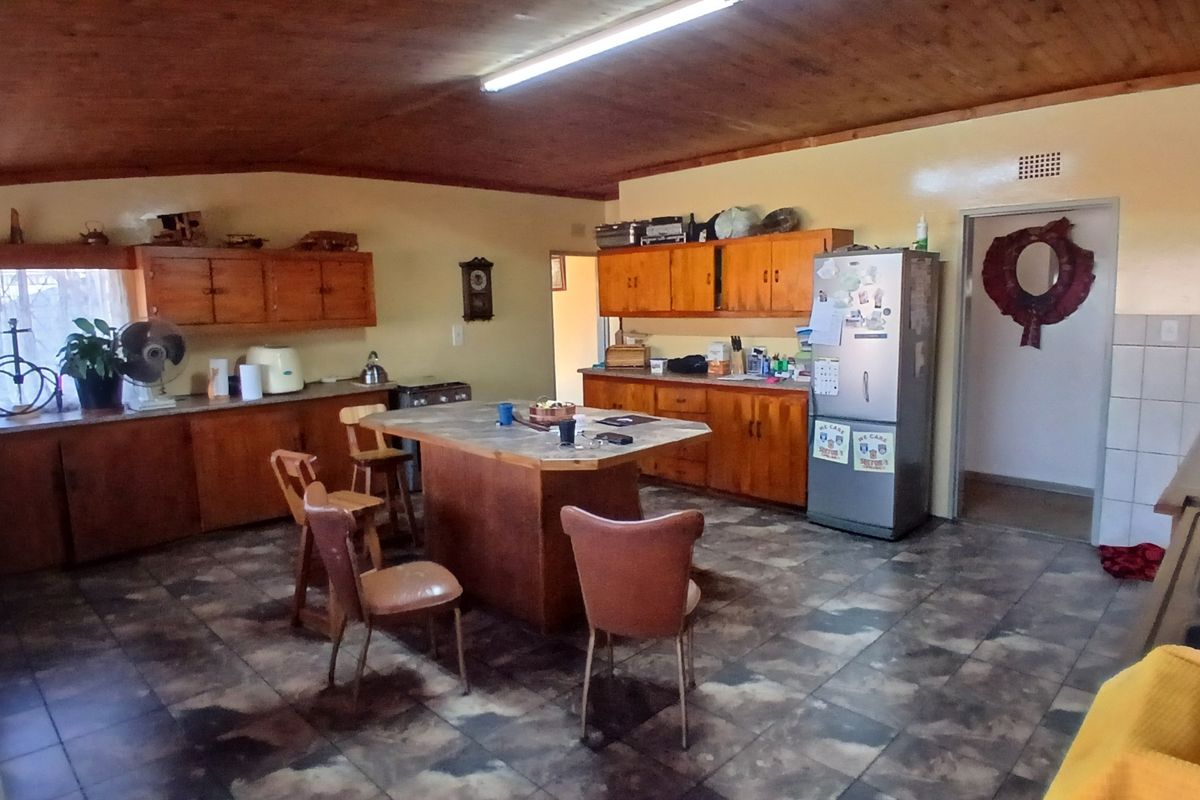Spacious kitchen featuring wooden cabinetry, a central island, and tiled flooring, offering a functional layout with potential for modern updates.