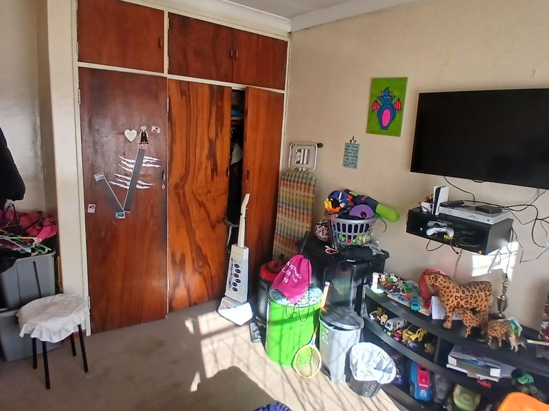 A bedroom featuring a full-height built-in wooden wardrobe and carpeted flooring.