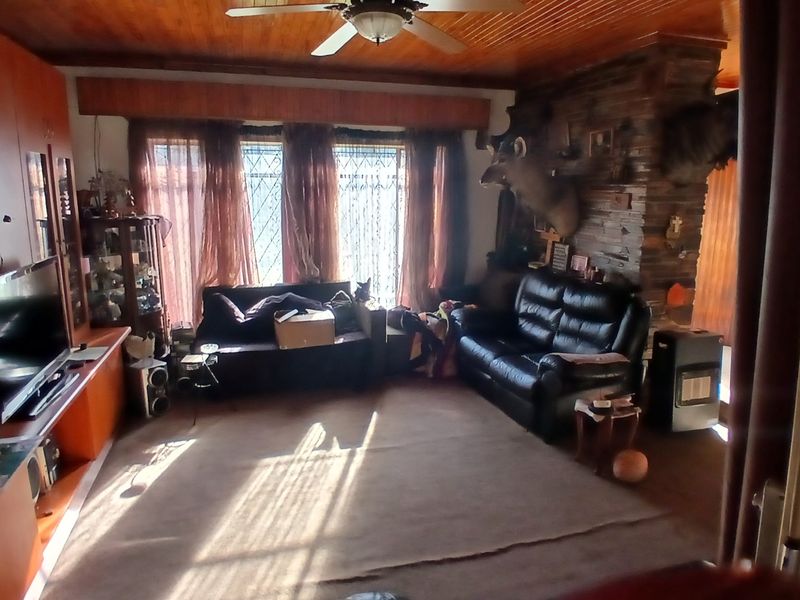 A living room featuring a stone-clad fireplace, wood-paneled ceiling, and built-in cabinetry, providing a traditional and cozy atmosphere.