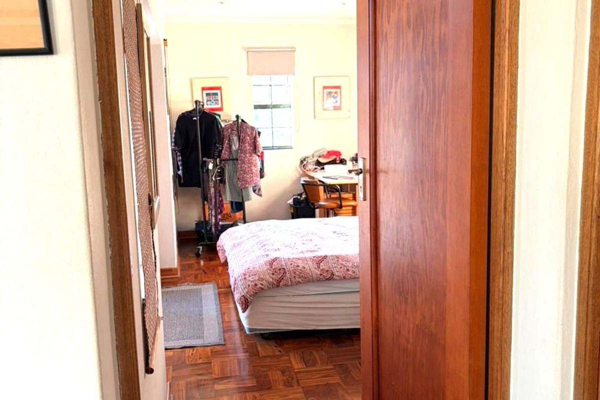 A bedroom featuring classic parquet flooring and a solid timber door, viewed from the hallway entrance.
