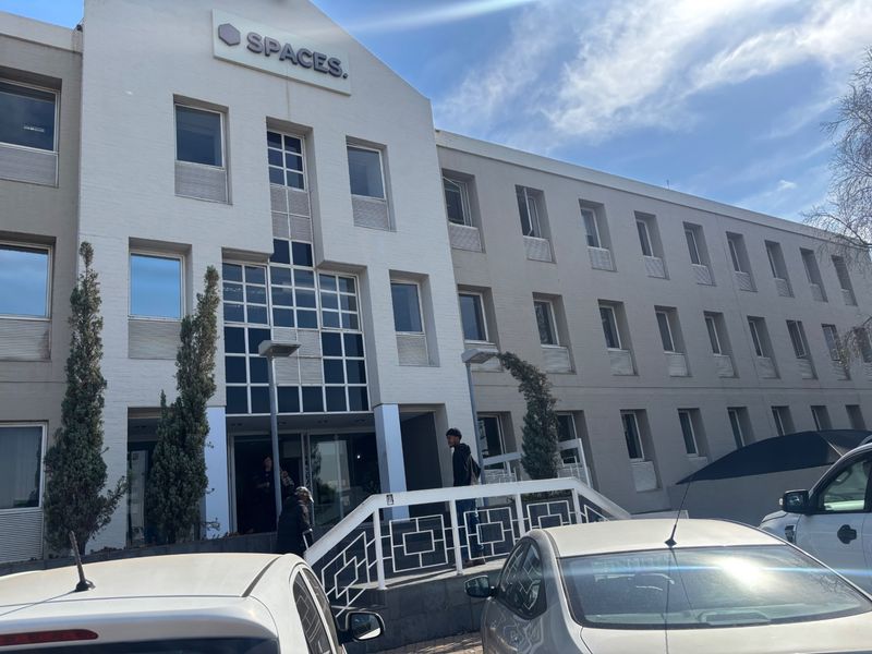 Front elevation of a multi-story commercial office building featuring a prominent entrance, modern facade, and exterior signage.