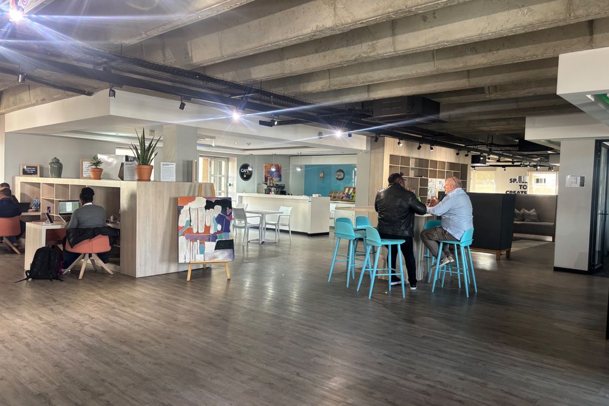 Spacious open-plan commercial area featuring exposed concrete ceilings, modern track lighting, and integrated service counters suitable for a collaborative office or cafe environment.