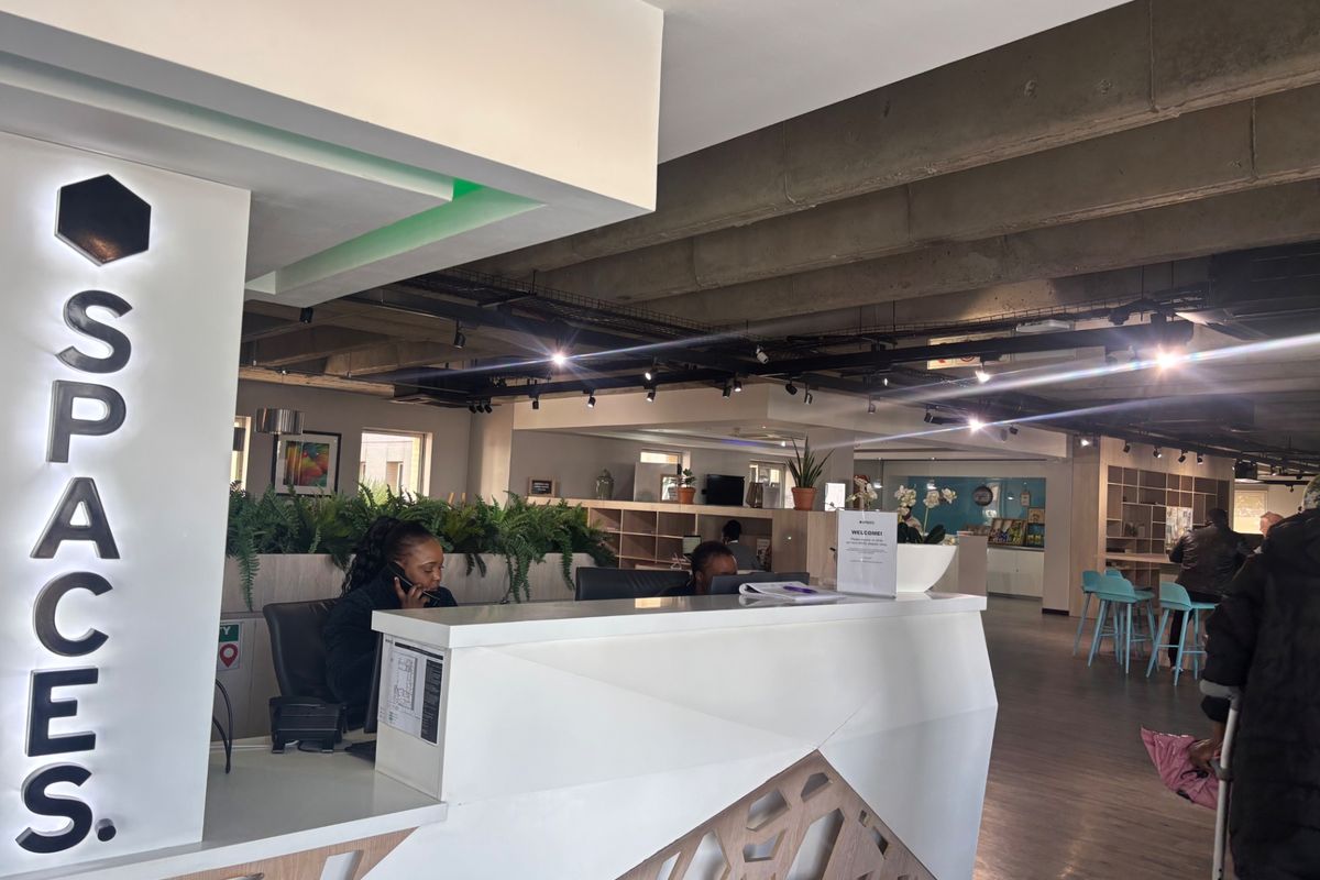 Modern commercial reception area featuring a contemporary desk, exposed concrete ceiling, and professional track lighting in a well-maintained office environment.
