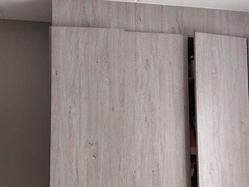 A bedroom featuring modern, light wood-grain built-in cupboards with clean lines.