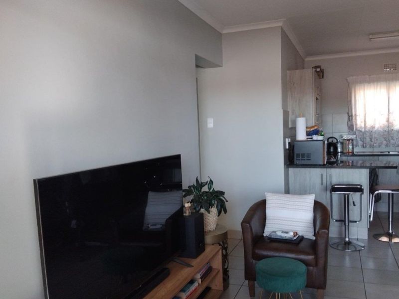Open plan living area featuring tiled flooring and a functional kitchen with granite countertops and a breakfast bar.