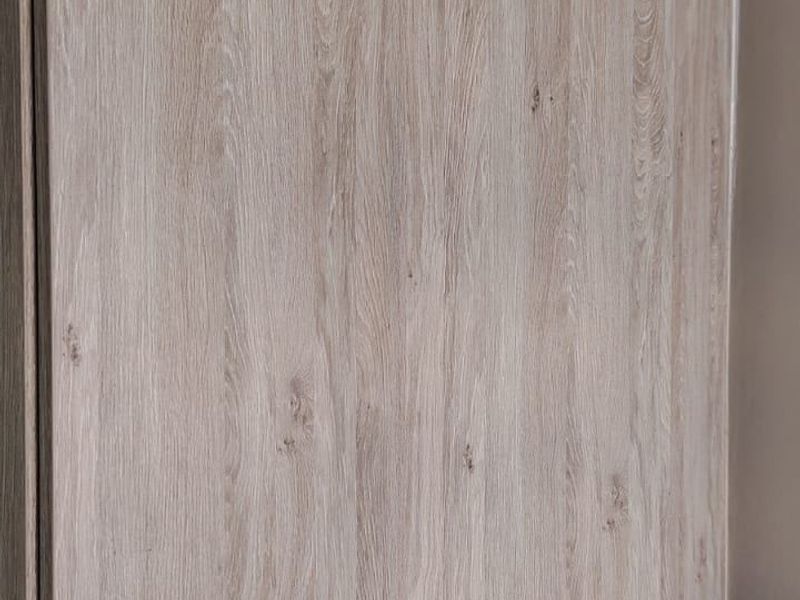 A close-up view of modern, wood-grain finish built-in cupboards with sleek metal handles, providing ample storage space.