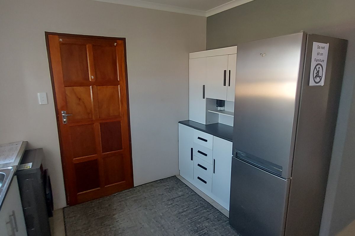 A functional kitchen area featuring built-in cabinetry, a stainless steel sink with mixer tap, and a solid timber door.