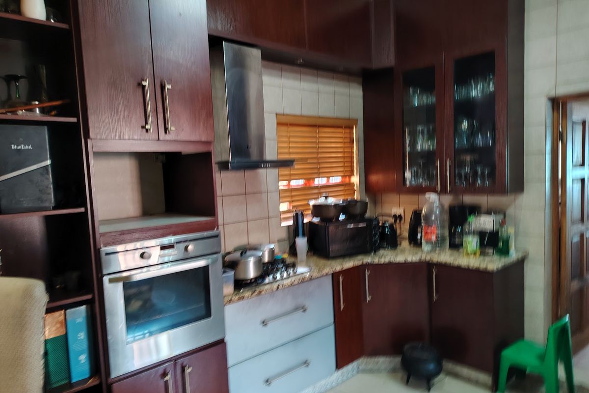 A functional kitchen featuring dark wood cabinetry, granite countertops, a built-in oven, and a stainless steel extractor fan.