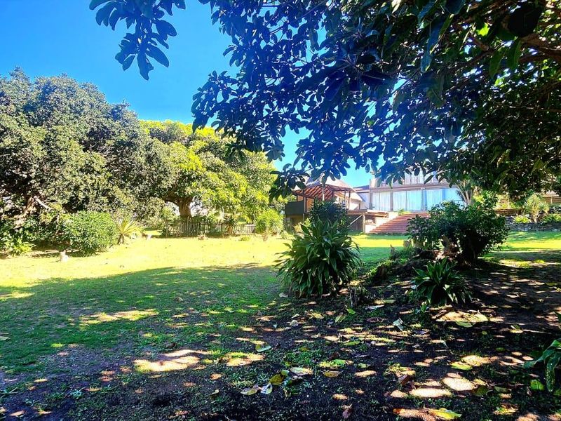 A spacious, well-established garden featuring mature trees and a large lawn area, providing a private and serene outdoor setting.