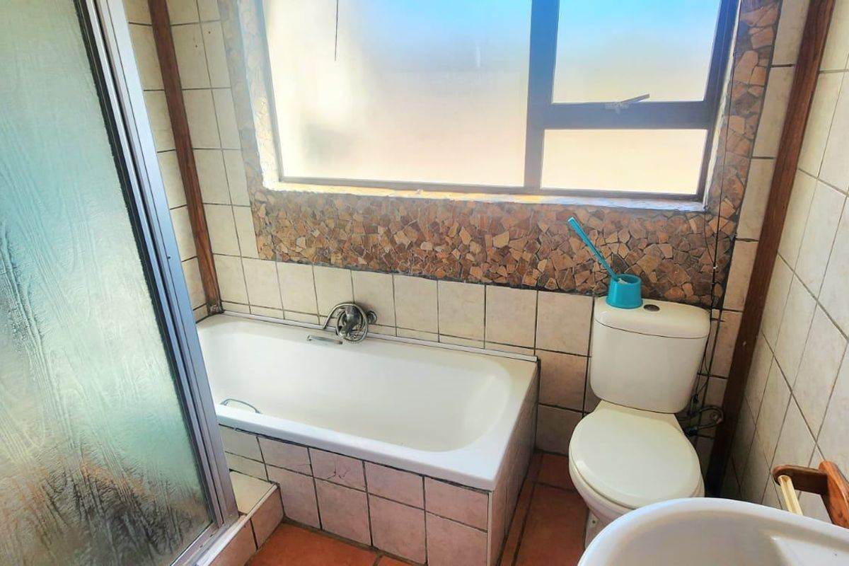 A dated bathroom featuring a built-in bathtub, shower enclosure, pedestal basin, and toilet, finished with ceramic wall and floor tiles.