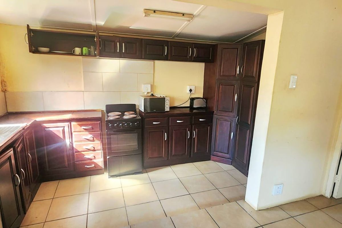 A functional kitchen featuring dark wood cabinetry, tiled backsplash, and ceramic flooring, offering a dated aesthetic with potential for modernization.