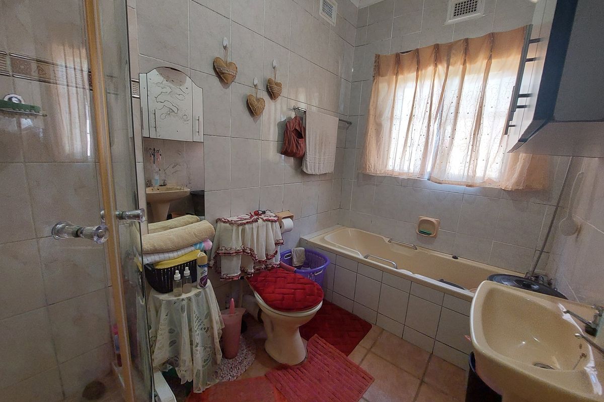A dated bathroom featuring a built-in bathtub, pedestal basin, and a separate glass-enclosed shower with full-height wall tiling.