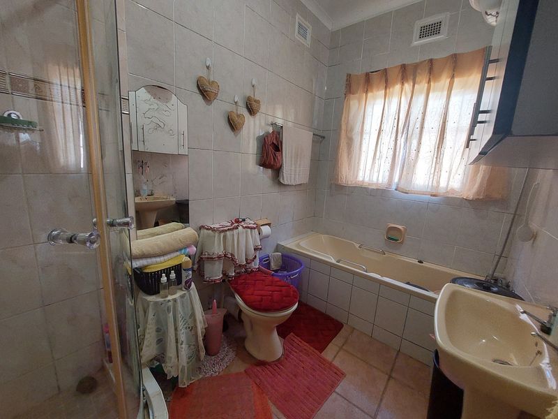 A dated bathroom featuring a built-in bathtub, pedestal basin, and a separate glass-enclosed shower with full-height wall tiling.
