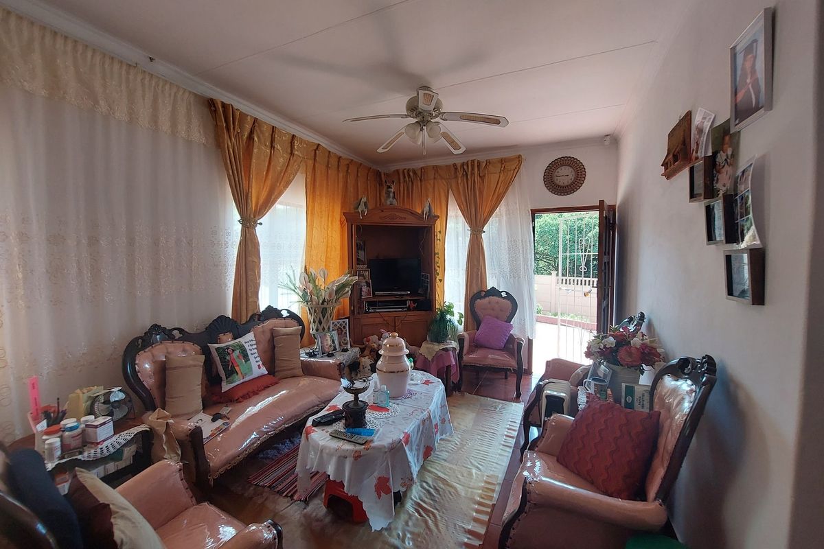 A cozy living room featuring tiled flooring, a ceiling fan, and direct access to an outdoor area through a security gate.