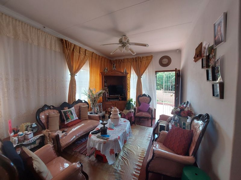 A cozy living room featuring tiled flooring, a ceiling fan, and direct access to an outdoor area through a security gate.