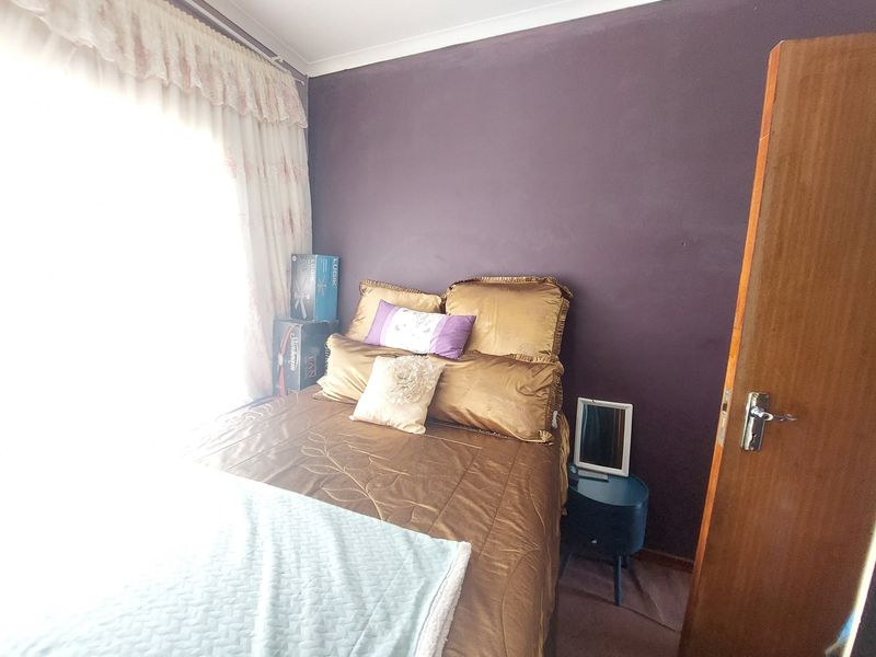 A bedroom featuring dark purple accent wall paint, timber door, and coving detail. The room requires cosmetic updates to improve its overall aesthetic appeal.
