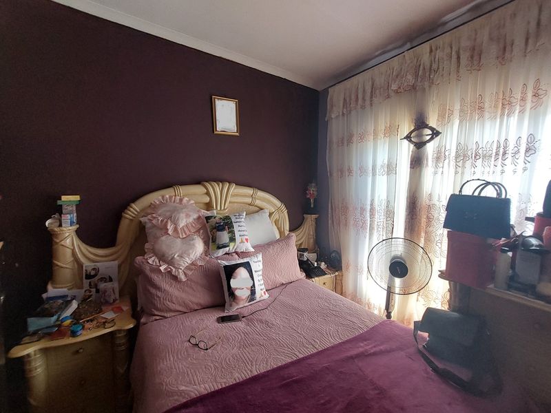 A bedroom featuring a dark accent wall and large window with decorative curtains, providing natural light to the space.