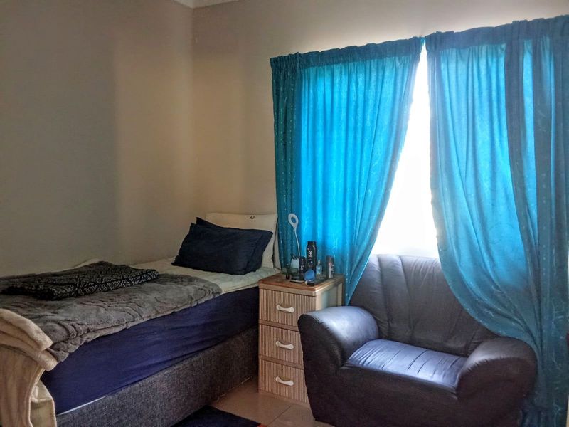 A standard bedroom featuring a window with curtains, providing natural light and basic living space.