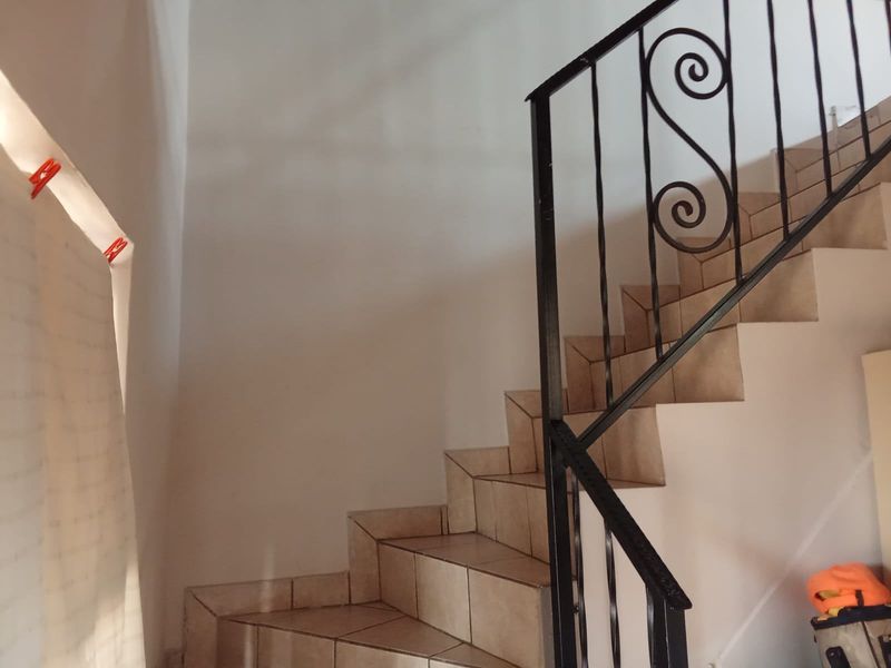 A staircase featuring tiled steps and a decorative wrought iron balustrade, providing access between levels in the apartment.
