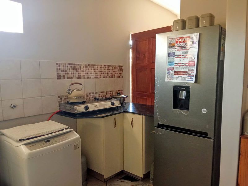 A compact kitchen area featuring granite countertops, tiled backsplash, and built-in cabinetry, providing functional preparation space.