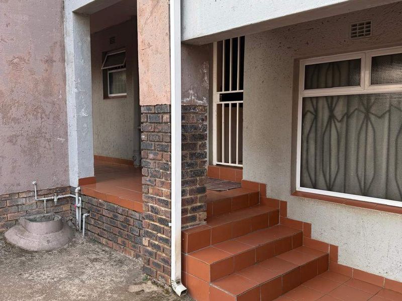 Exterior view of the townhouse entrance featuring tiled steps, a covered porch area, and brick masonry detailing.