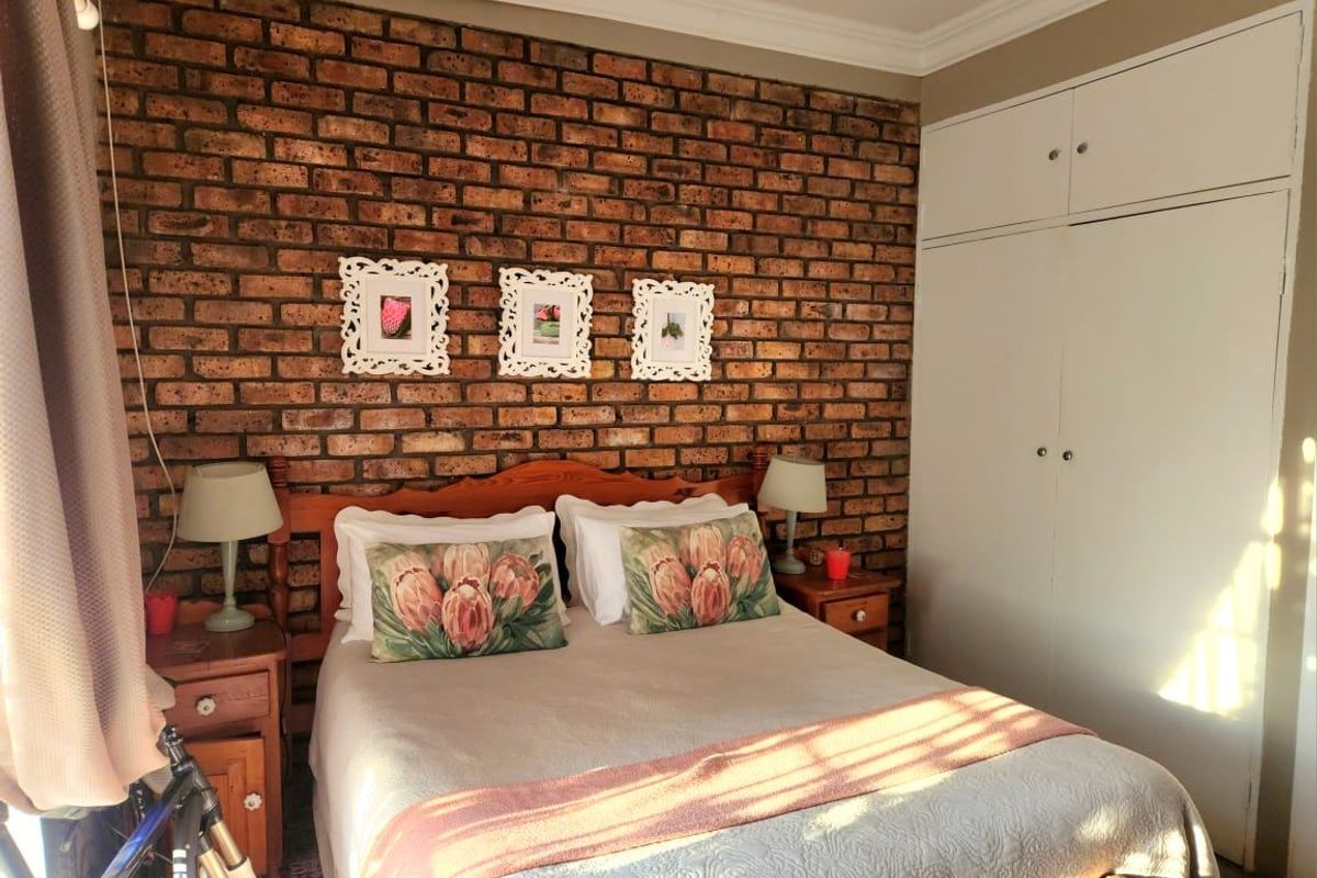 A cozy bedroom featuring an exposed brick feature wall and ample built-in cupboard storage.