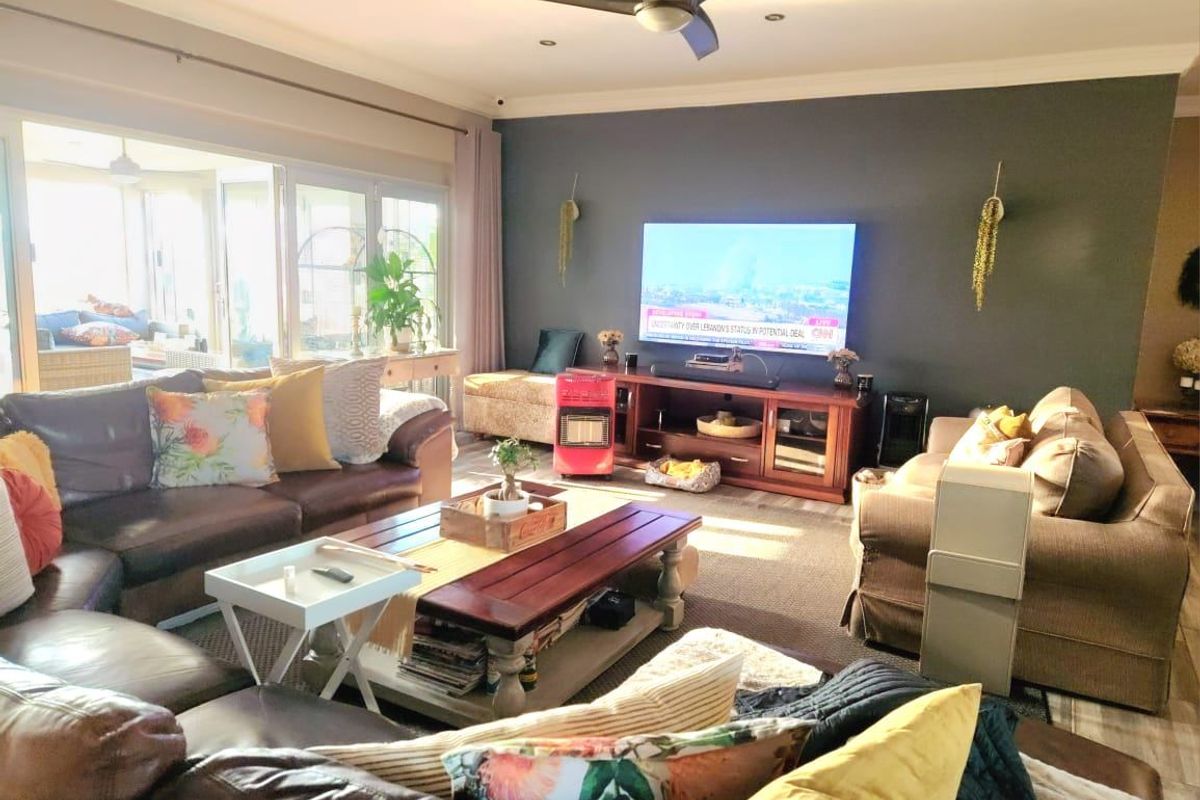 Spacious living room featuring a dark accent wall, recessed ceiling lighting, a ceiling fan, and large sliding glass doors leading to an outdoor area.