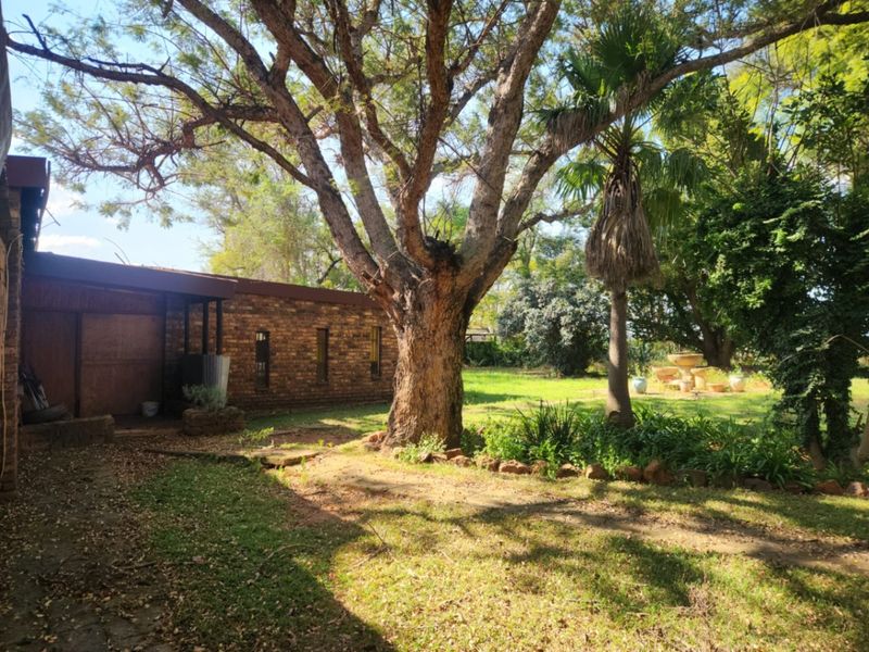 A view of the rear garden featuring mature trees, a stone fountain, and a face brick exterior wall of the farm dwelling.