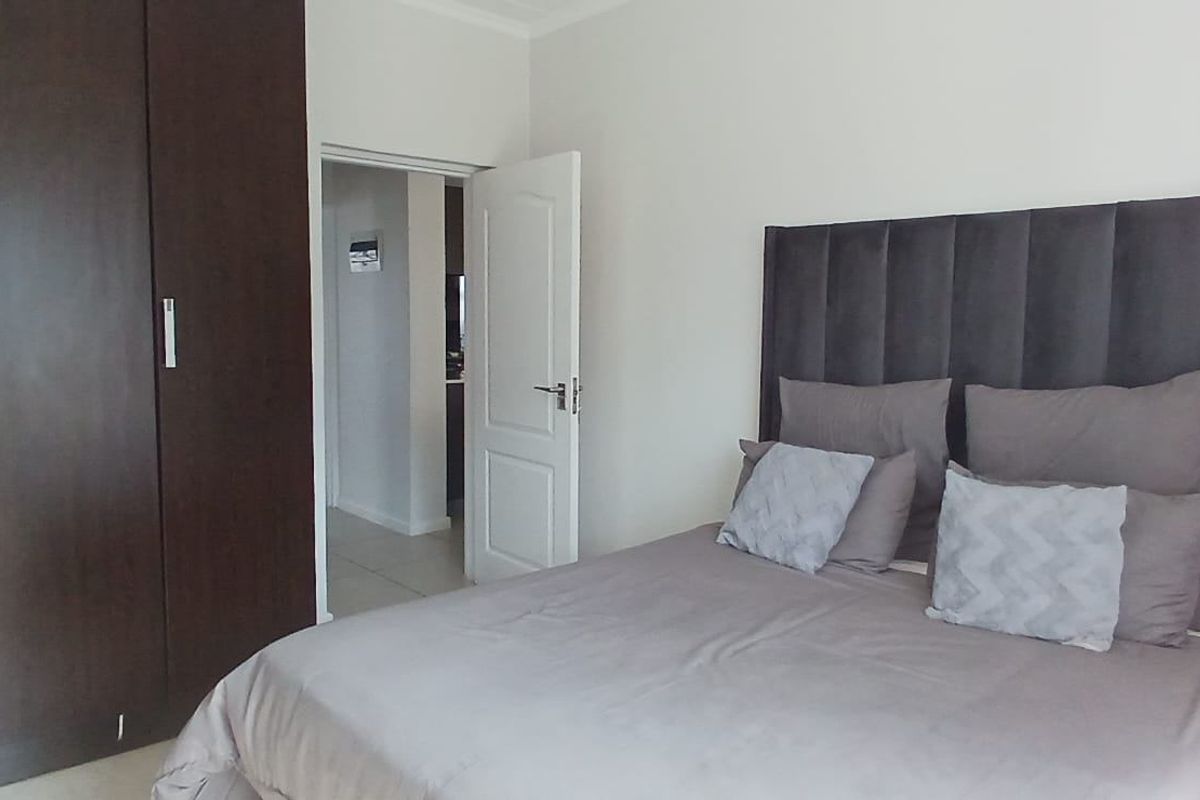 A well-maintained bedroom featuring dark wood built-in cupboards and neutral tiled flooring, offering a clean and functional living space.