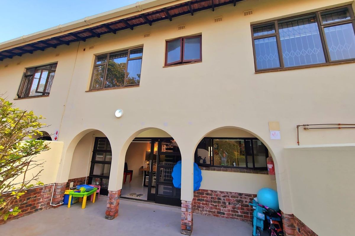 Rear elevation of the townhouse featuring a covered patio with arched brick-based columns, tiled roof, and aluminium-framed windows with security bars.