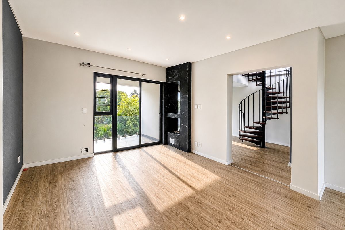 A bright, modern living room featuring laminate flooring, a striking marble-clad fireplace, and a spiral staircase leading to the upper level.