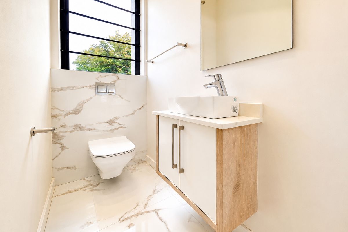 Modern bathroom featuring a wall-mounted toilet, floating vanity with vessel sink, and elegant marble-look floor and wall tiling.