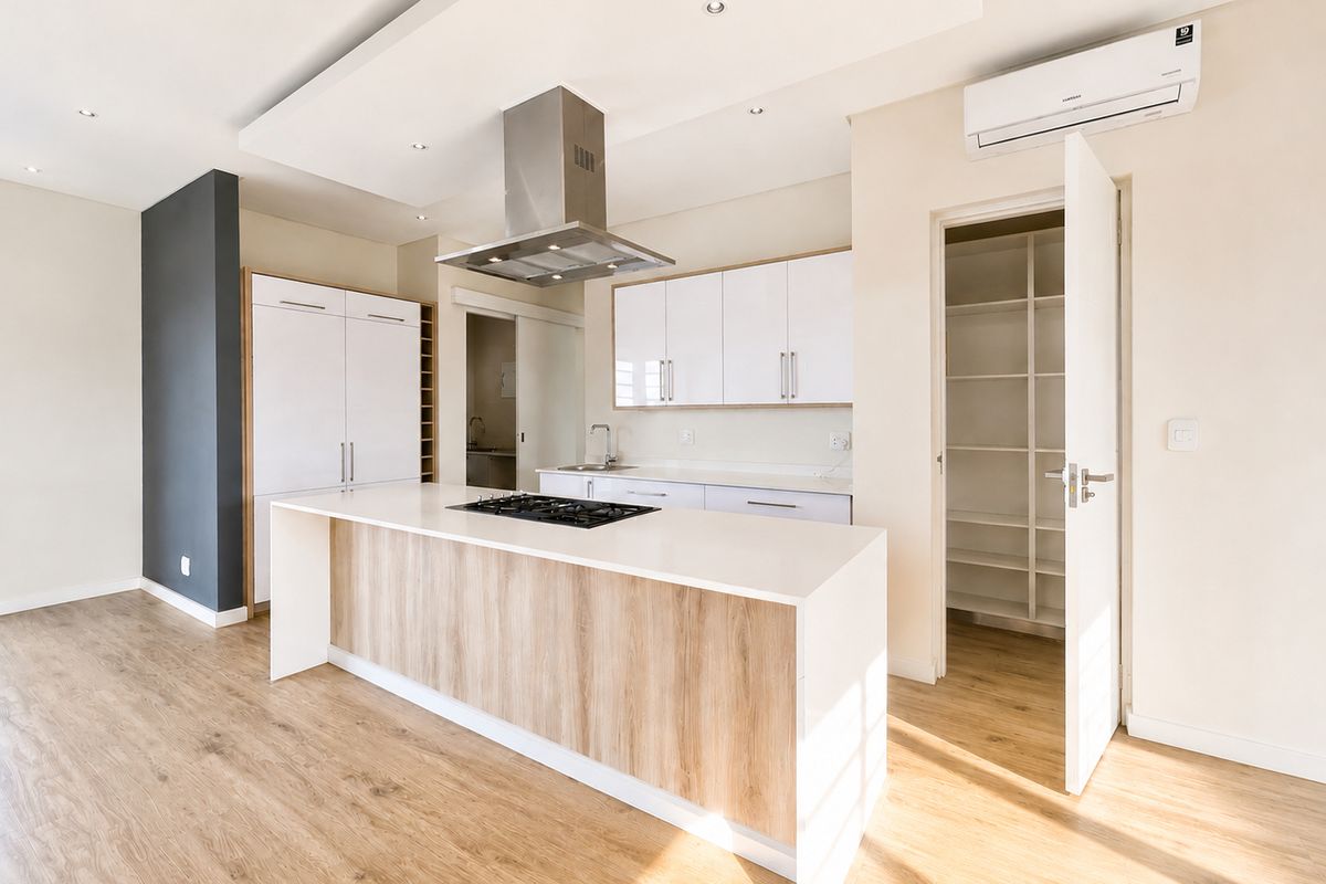 Modern open-plan kitchen featuring a central island with gas hob, sleek white cabinetry, integrated extractor fan, and a convenient walk-in pantry.