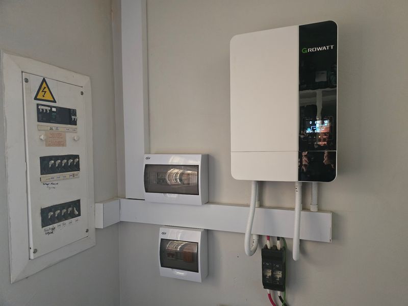 A clean utility area featuring a modern Growatt solar inverter and electrical distribution board with organized conduit trunking.