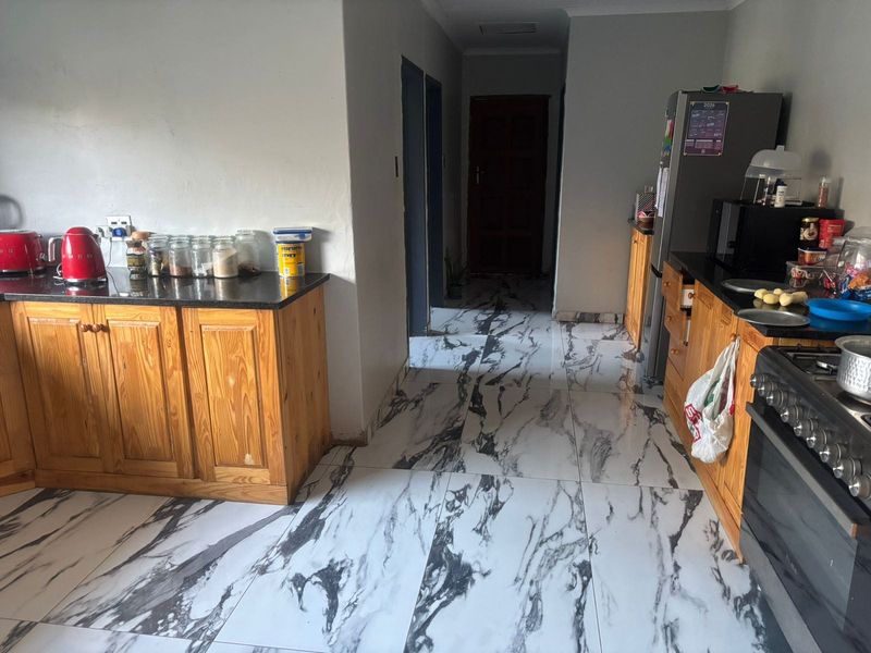 Kitchen featuring wooden cabinetry, granite countertops, and a gas stove, finished with marble-effect floor tiles.