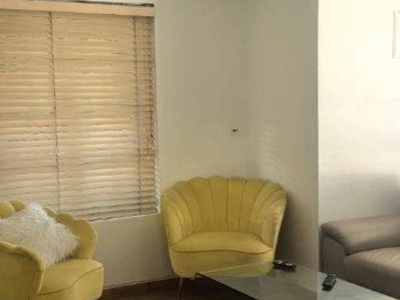 A living room area featuring tiled flooring, venetian blinds, and a ceiling light fixture, showing signs of wear including a visible ceiling crack.