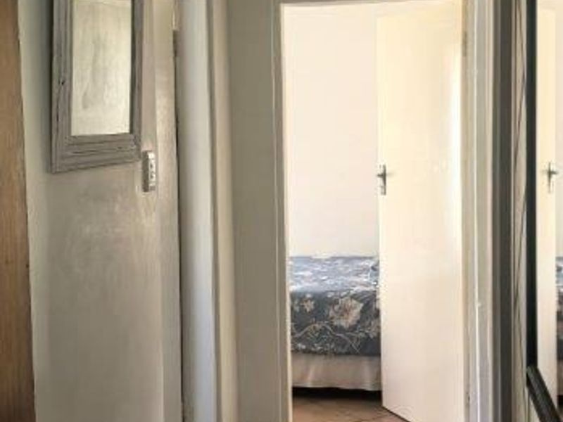 A functional hallway featuring tiled flooring and a ceiling access hatch, providing access to adjacent rooms.