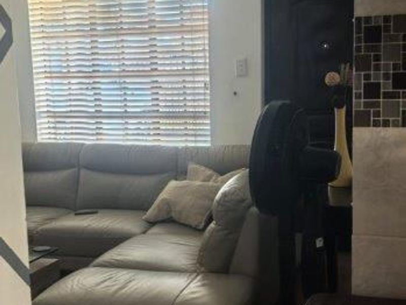 A living room area featuring tiled flooring, recessed lighting, and venetian blinds on the window.
