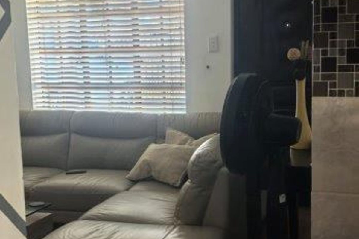 A living room area featuring tiled flooring, recessed lighting, and venetian blinds on the window.